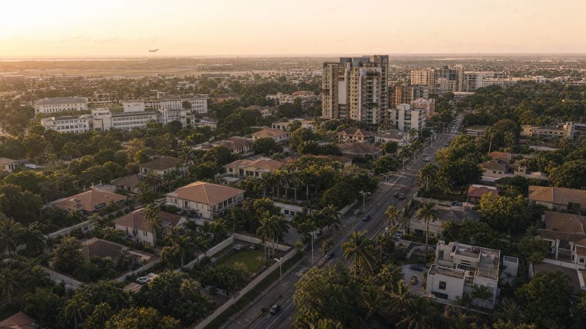An aerial view over the Airport Residential Area at sunset, with an aircraft climbing away from Kotoka International