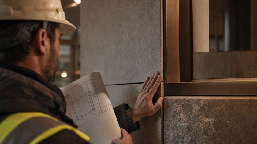 A site engineer checking a stone cladding joint against technical drawings